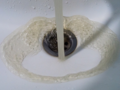 Water flowing into a sink drain, illustrating backflow prevention importance in plumbing.