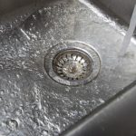 Water flowing into a stainless steel sink drain, illustrating the importance of effective drain cleaning services by Southside Plumbing in Omaha, NE.